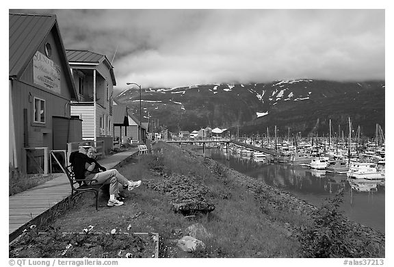 Couple sitting on bench by the harbor. Whittier, Alaska, USA (black and white)