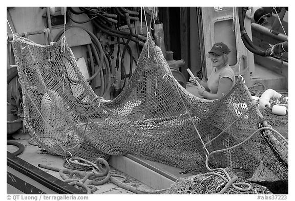 Woman repairing net on fishing boat. Whittier, Alaska, USA