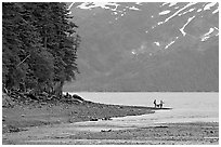 Women fishing and dog, at the edge of Passage Canal Fjord. Whittier, Alaska, USA (black and white)