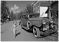 Girl on main street with red classic car. McCarthy, Alaska, USA (black and white)