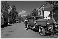 Woman walking next to red classic car. McCarthy, Alaska, USA (black and white)