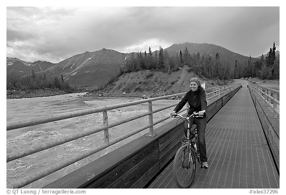 Woman on mountain bike crossing the footbridge. McCarthy, Alaska, USA (black and white)