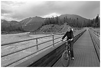 Woman on mountain bike crossing the footbridge. McCarthy, Alaska, USA (black and white)