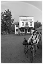 Women with bikes, hotel, and rainbow. McCarthy, Alaska, USA (black and white)