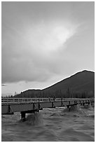 Footbridge with the Kennicott River swelled from the annual Hidden Lake flood. McCarthy, Alaska, USA ( black and white)