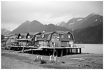 Stilt houses on the Spit, Kenai Mountains in the backgound. Homer, Alaska, USA (black and white)