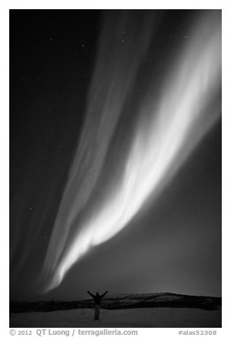 Aurora Borealis streaming above person with outstretched arms. Alaska, USA (black and white)