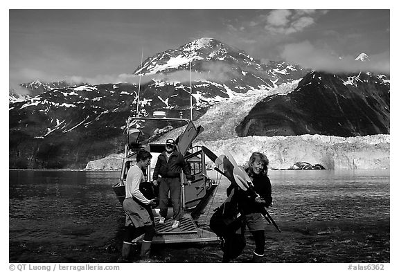 Kayakers unloading kayak from water taxi boat at Black Sand Beach. Prince William Sound, Alaska, USA (black and white)