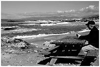 Man reading on a picnic table, Bean Hollow State Beach. San Mateo County, California, USA (black and white)