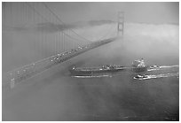 Tanker ship cruising under the Golden Gate Bridge in the fog. San Francisco, California, USA (black and white)
