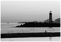 Lighthouse and Surfers in the water at sunset. Santa Cruz, California, USA (black and white)
