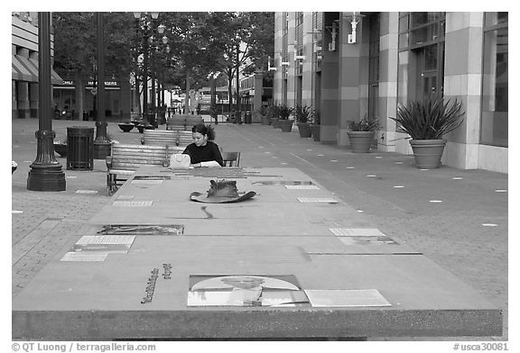 Woman sitting at a commemorative table in a downtown alley. San Jose, California, USA