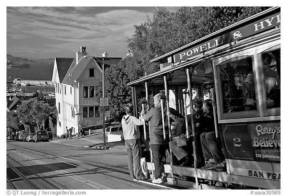 Cable car plunging with people clinging on Hyde Street, late afternoon. San Francisco, California, USA (black and white)
