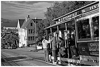 Cable car plunging with people clinging on Hyde Street, late afternoon. San Francisco, California, USA ( black and white)