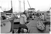 Pier with passengers preparing to board a tour boat with outdoor gear, Ventura. California, USA (black and white)