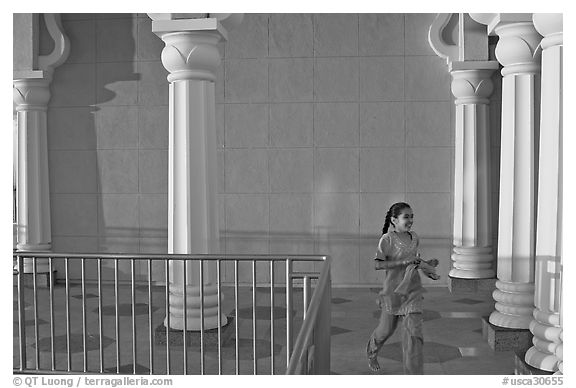 Indian girl running in the Sikh Gurdwara Temple, late afternoon. San Jose, California, USA (black and white)