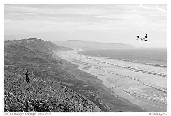 Man piloting model glider, Fort Funston, late afternoon. San Francisco, California, USA (black and white)