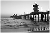 The 1853 ft Huntington Pier reflected in wet sand at sunset. Huntington Beach, Orange County, California, USA (black and white)