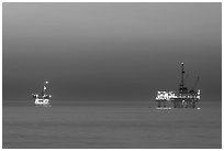 Oil drilling platforms lighted at dusk. Huntington Beach, Orange County, California, USA ( black and white)