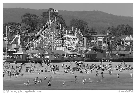 Beachgoers, and Santa Cruz boardwalk roller-coaster. Santa Cruz, California, USA (black and white)