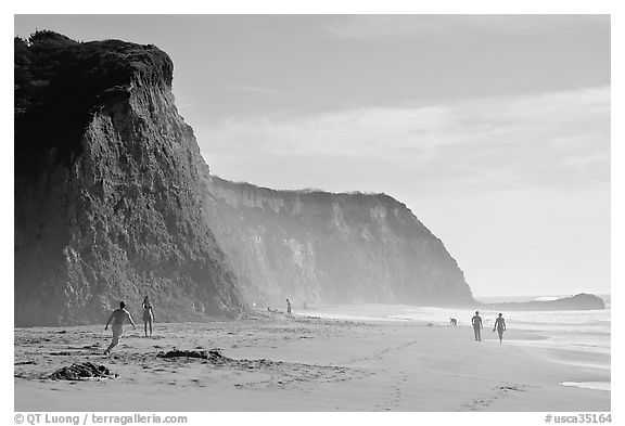 People strolling and playing below cliffs, Scott Creek Beach. California, USA (black and white)