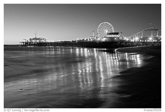 Pier and Ferris Wheel reflected on beach at dusk. Santa Monica, Los Angeles, California, USA (black and white)