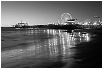 Pier and Ferris Wheel reflected on beach at dusk. Santa Monica, Los Angeles, California, USA (black and white)