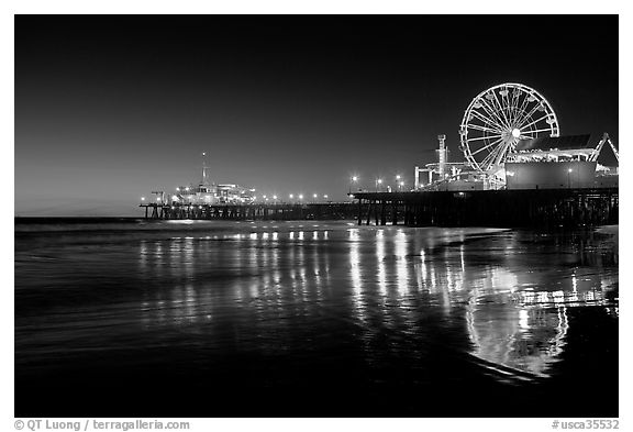 Ferris Wheel and pier reflected on wet sand at night. Santa Monica, Los Angeles, California, USA (black and white)