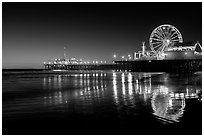 Ferris Wheel and pier reflected on wet sand at night. Santa Monica, Los Angeles, California, USA (black and white)