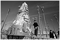 Man painting inscriptions on a graffiti-decorated tower. Venice, Los Angeles, California, USA (black and white)