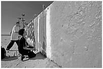 Young men creating graffiti art on a wall on the beach. Venice, Los Angeles, California, USA ( black and white)