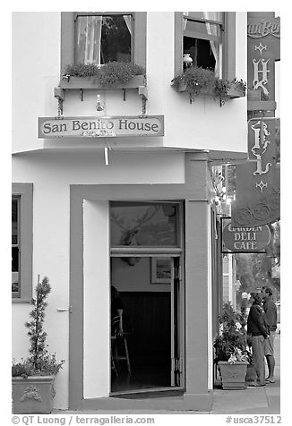 Entrance of historic San Benito House, with couple looking. Half Moon Bay, California, USA (black and white)