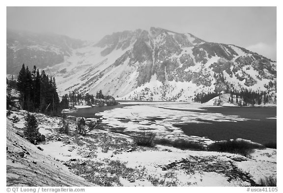 Partly frozen Ellery Lake and mountains with snow. California, USA (black and white)