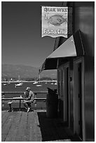 Man eating on wharf next to Fish and Chips restaurant. Santa Barbara, California, USA (black and white)