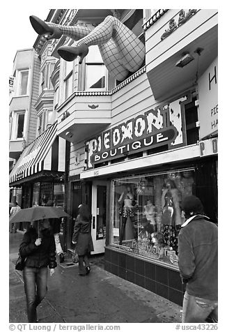 Woman passing with unbrella below giant legs. San Francisco, California, USA (black and white)