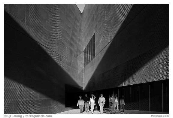 Tourists walking out of a striking corner of De Young Museum. San Francisco, California, USA (black and white)