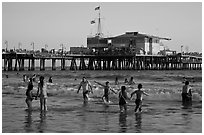 People bathing in ocean and Santa Monica Pier, late afternoon. Santa Monica, Los Angeles, California, USA (black and white)