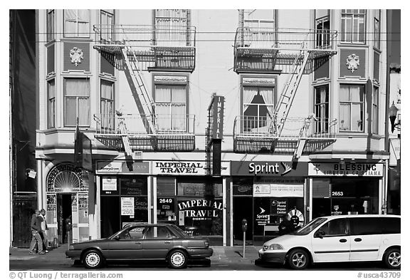 Buildings, cars, and sidewalk, Mission Street, Mission District. San Francisco, California, USA (black and white)