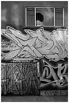 Mural paintings below broken window, Mission District. San Francisco, California, USA ( black and white)