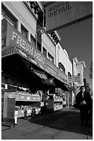 Woman walks past vegetable store, Mission Street, Mission District. San Francisco, California, USA (black and white)