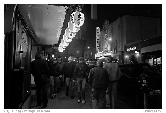 Men walking on sidewalk, Castro street at night. San Francisco, California, USA (black and white)