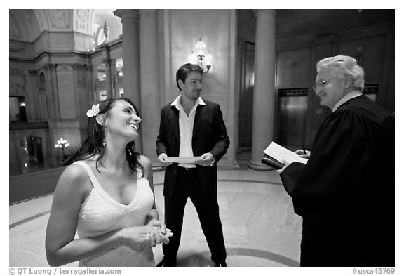 Bride and groom exchange smile with wedding official, City Hall. San Francisco, California, USA (black and white)