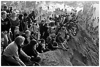 Spectators sitting on cliff to see mavericks contest. Half Moon Bay, California, USA ( black and white)
