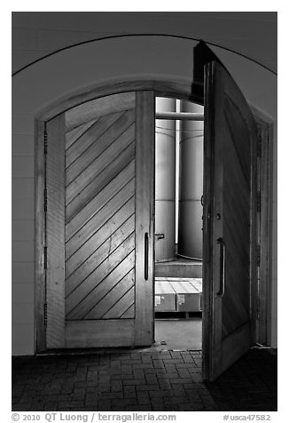 Wooden door opening to wine storage tanks. Napa Valley, California, USA (black and white)