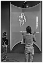 Girls play with thermal imaging camera, Tech Museum. San Jose, California, USA ( black and white)