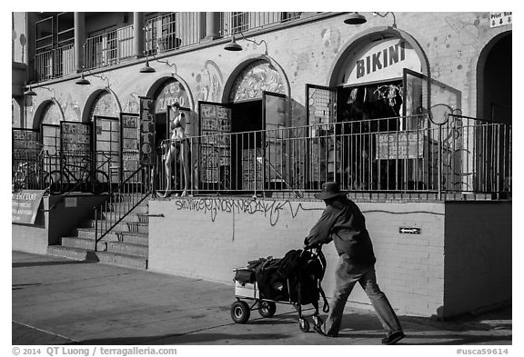 Man pushing cart in front of stores. Venice, Los Angeles, California, USA (black and white)