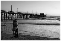 Couple embracing in front of Newport Pier. Newport Beach, Orange County, California, USA ( black and white)
