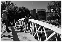 Boy fishing from arched bridge, Venice Canal Historic District. Venice, Los Angeles, California, USA ( black and white)