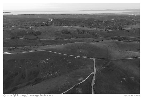 Aerial view of roads, gently rolling hills, with Pacific Ocean in the distance. California, USA (black and white)