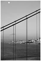 The city seen through the cables of the Golden Gate bridge, sunset. San Francisco, California, USA (black and white)